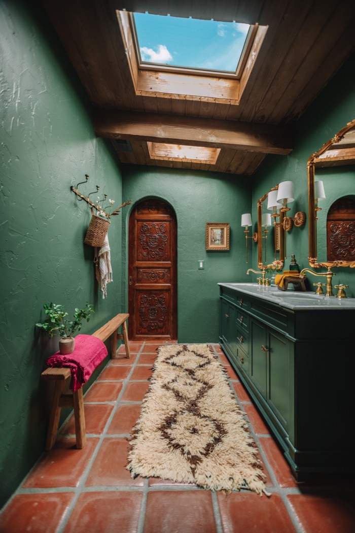 dark green bathroom with antique wood door in archway