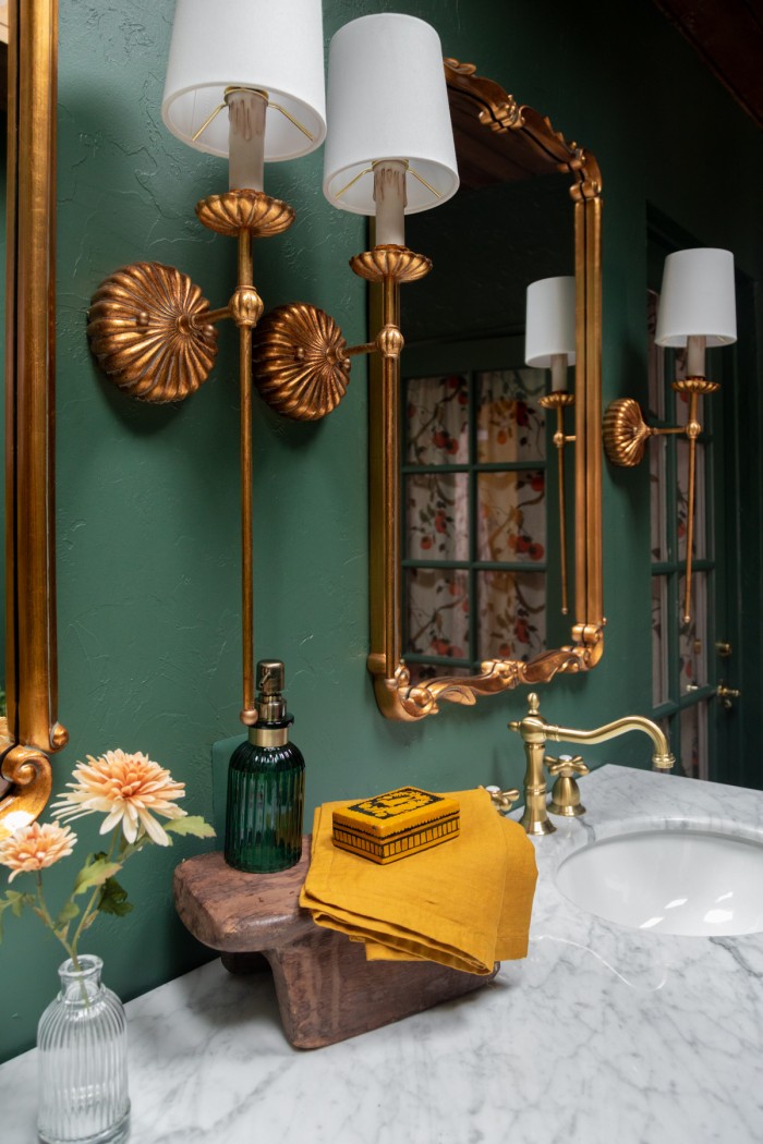 Brass lights and mirrors in green bathroom