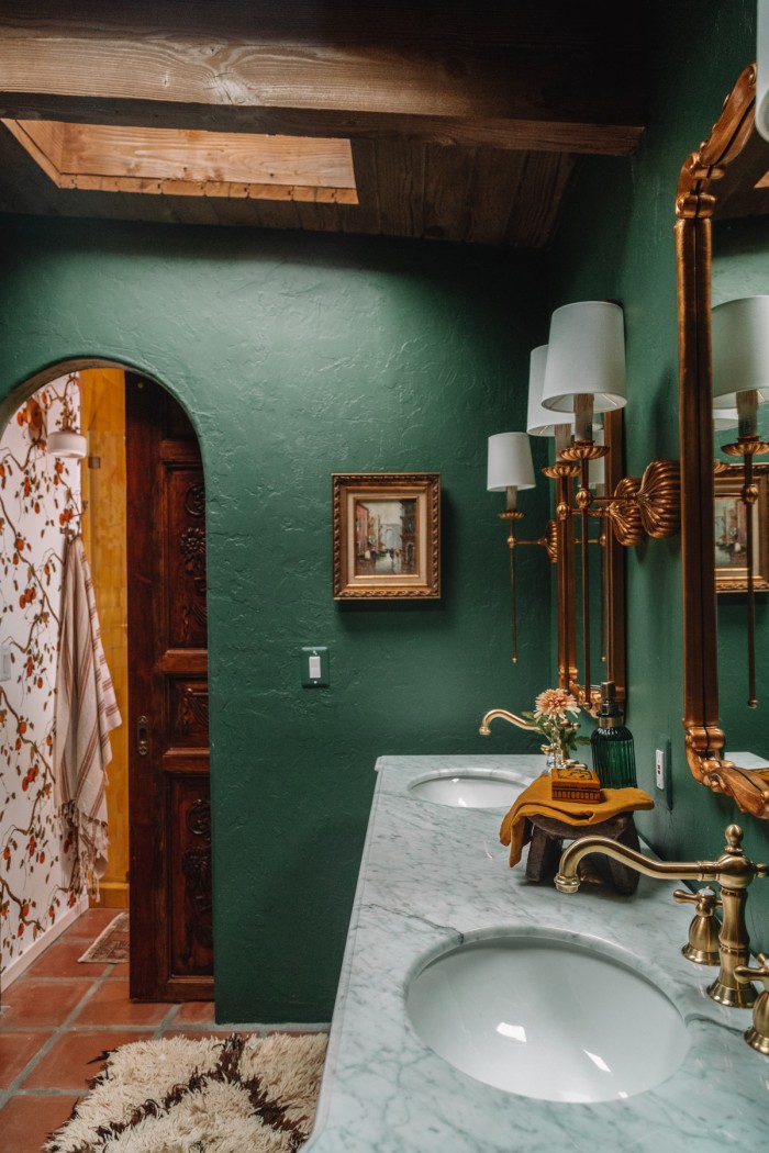 dark green bathroom with gold sconces