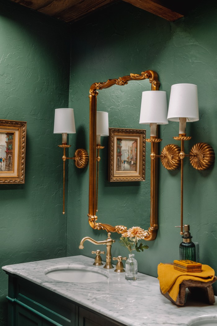 green bathroom with gold mirrors and sconces