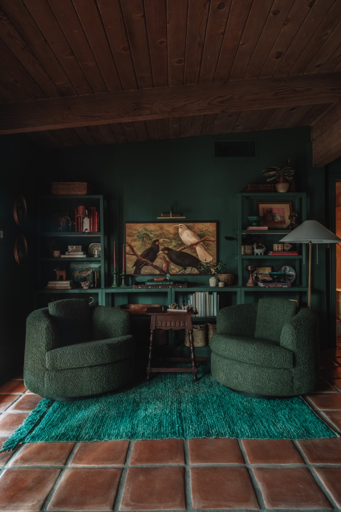 dark green chairs in monochromatic green bedroom with shelves