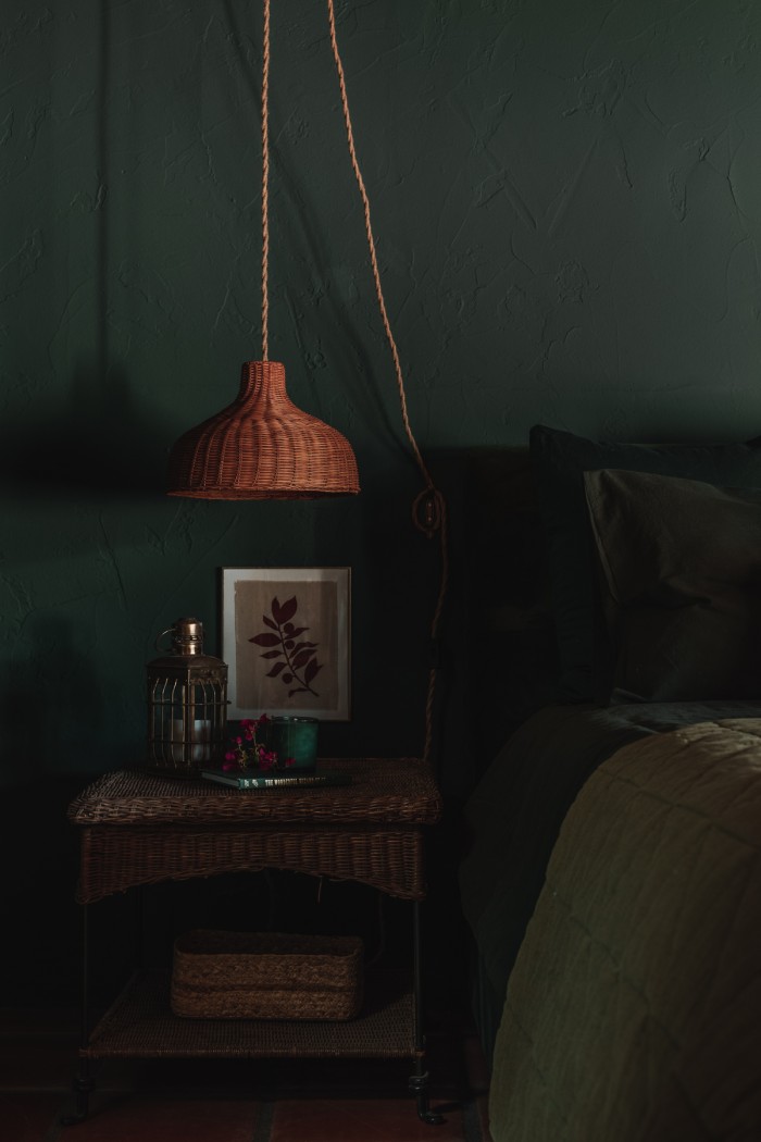 dark green bedroom with hanging rattan pendant sconces