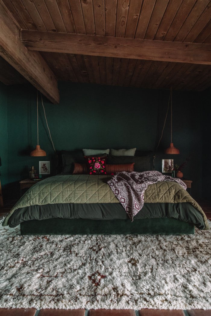 dark green bed with moroccan rug in green room