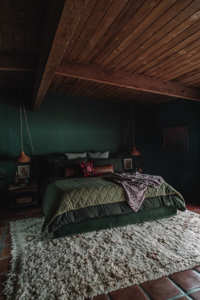 dark green bed in dark green room with wood ceilings