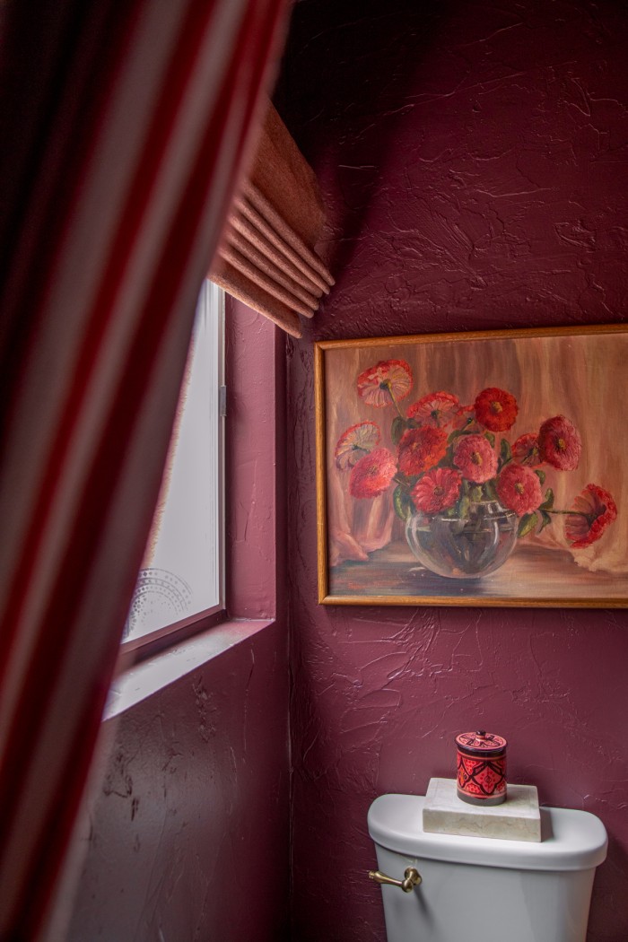 floral painting on purple wall with red stripe curtain in front