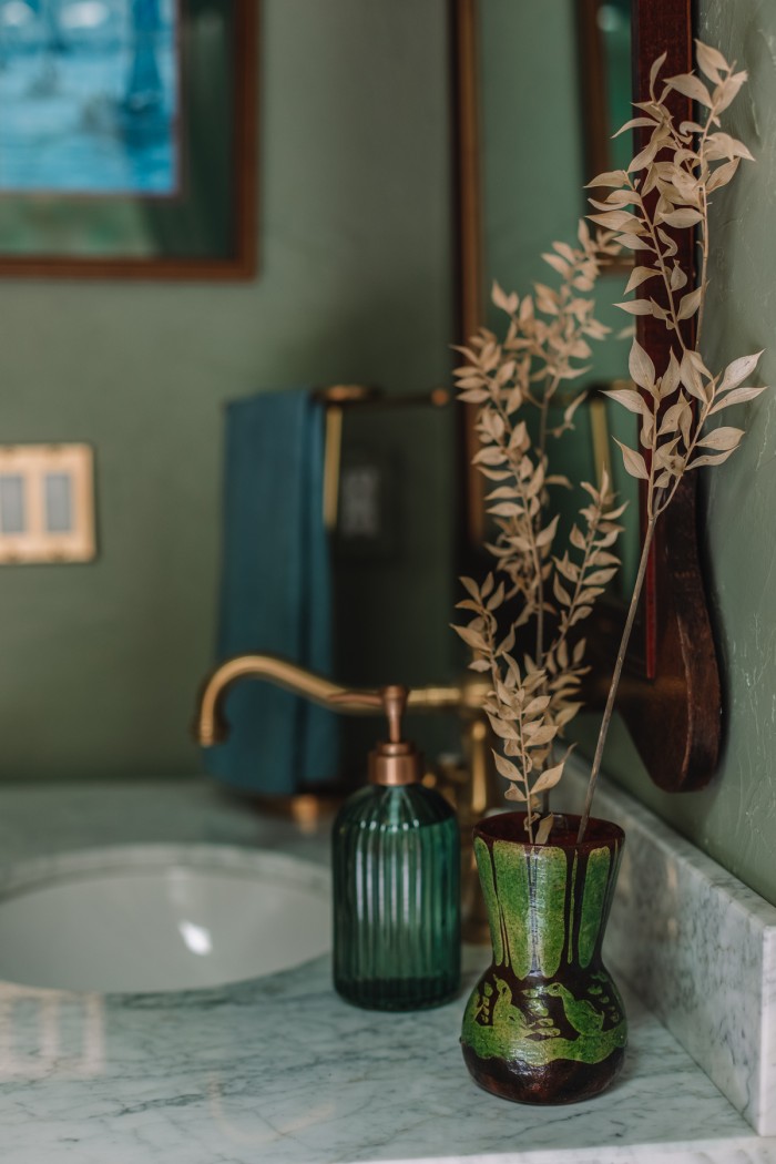 green vase on marble sink in green bathroom