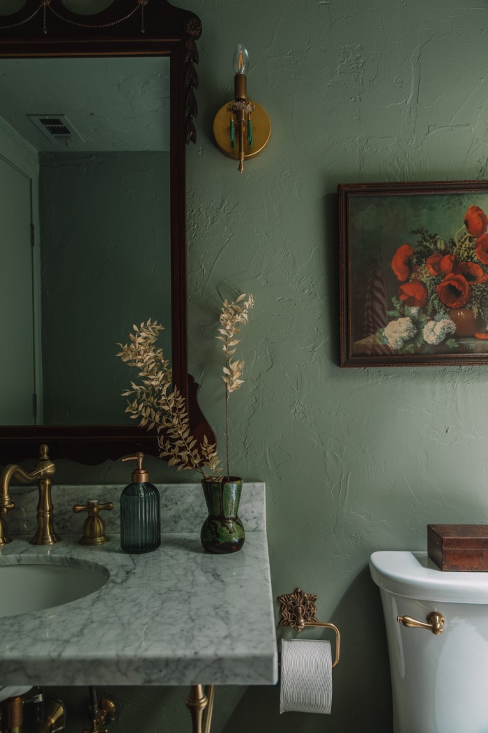 green bathroom with flower painting and tassel sconce