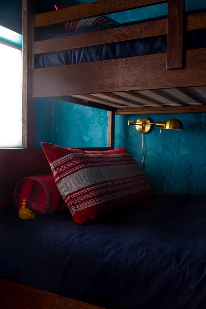 red pillow on bunk bed with gold reading light