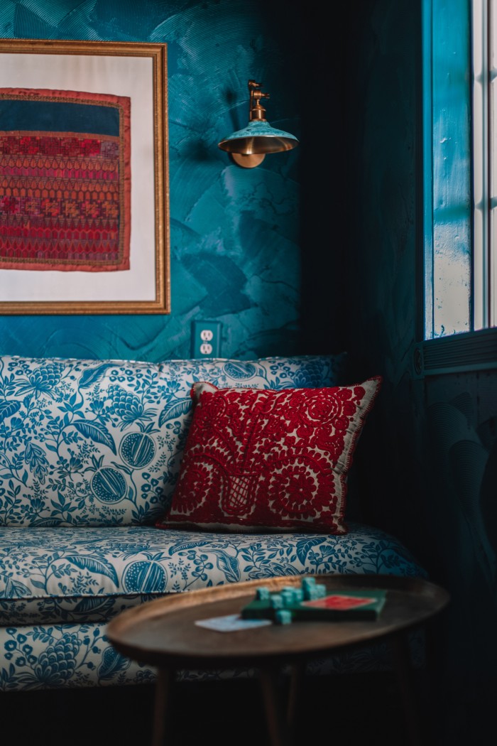 blue floral chair with red pillow in teal room