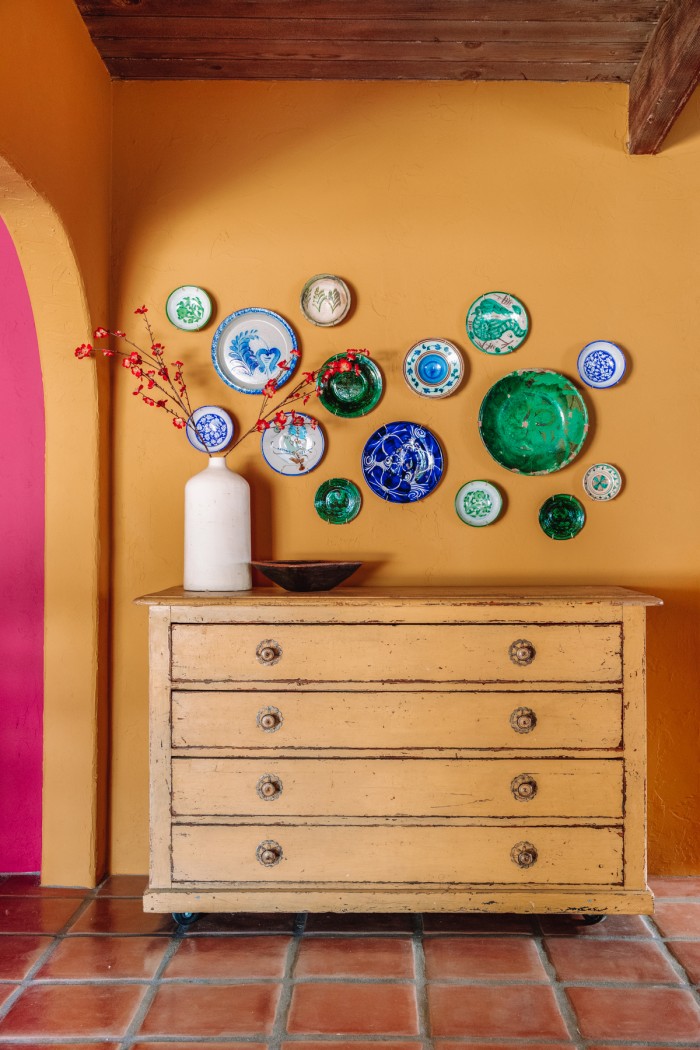 decorative plates on yellow wall above yellow chest