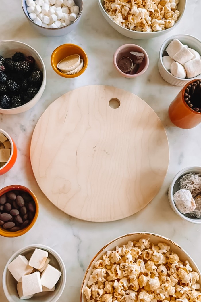 round cutting board on table surrounded by candy