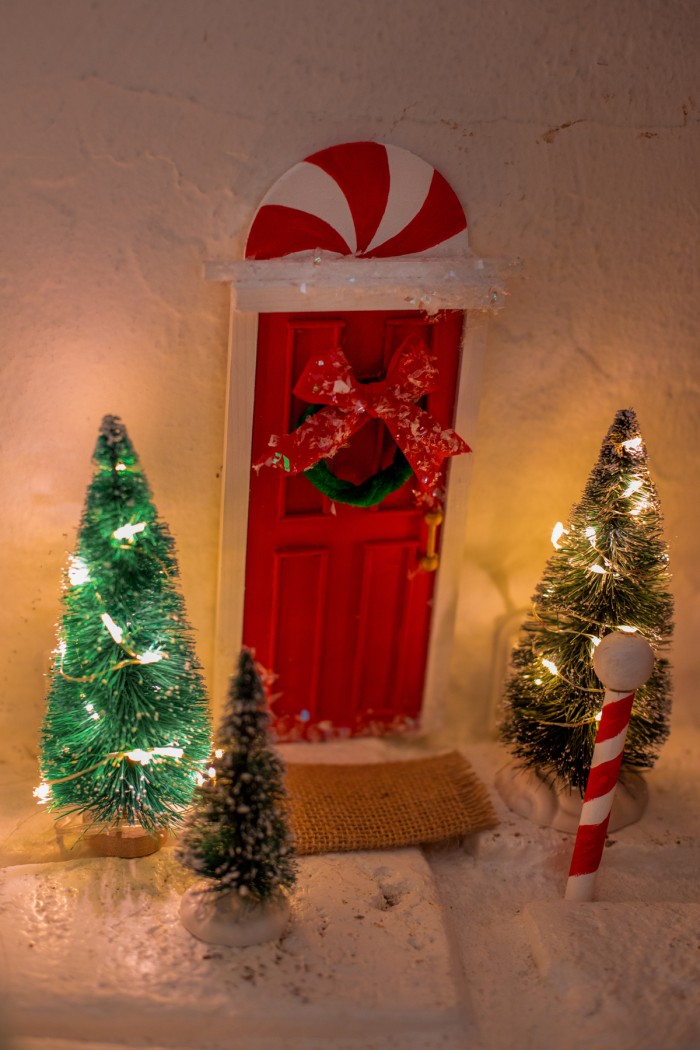 Elf door stuck to the wall with scene of trees and a north pole.