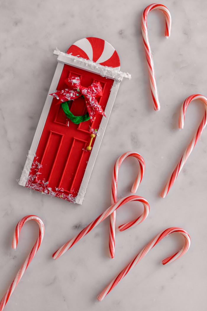 mini elf door laying on table with candy canes