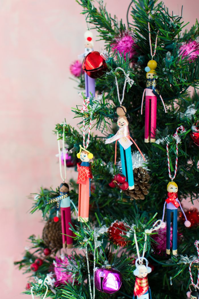 Clothespins decorated as people and made into ornaments hanging on a tree. 