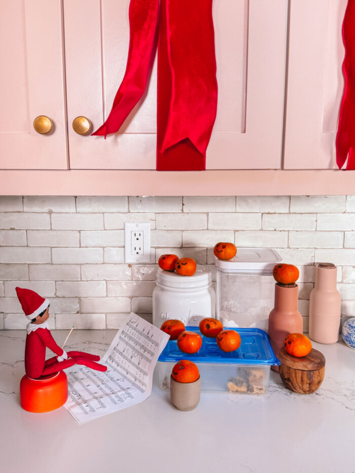 Elf on the Shelf conducting a choir of clementines