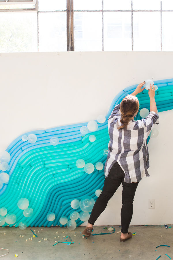 Woman setting up a water inspired balloon wall. 