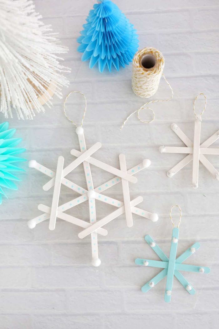 Popsicle stick snowflake ornaments on a brick background. 