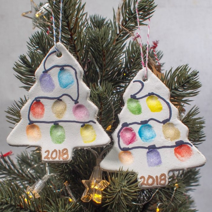 Two homemade Christmas tree ornaments hanging on a tree. 