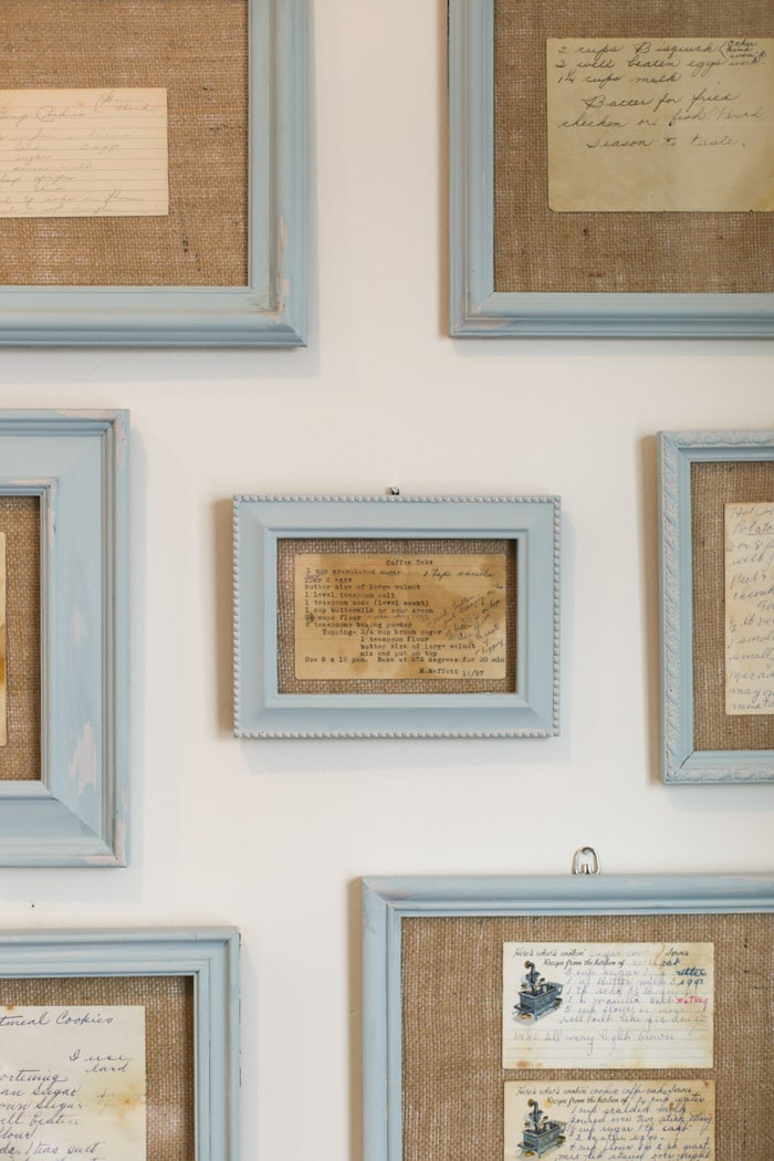 Light blue frames hung on a wall with heirloom recipes in them. 