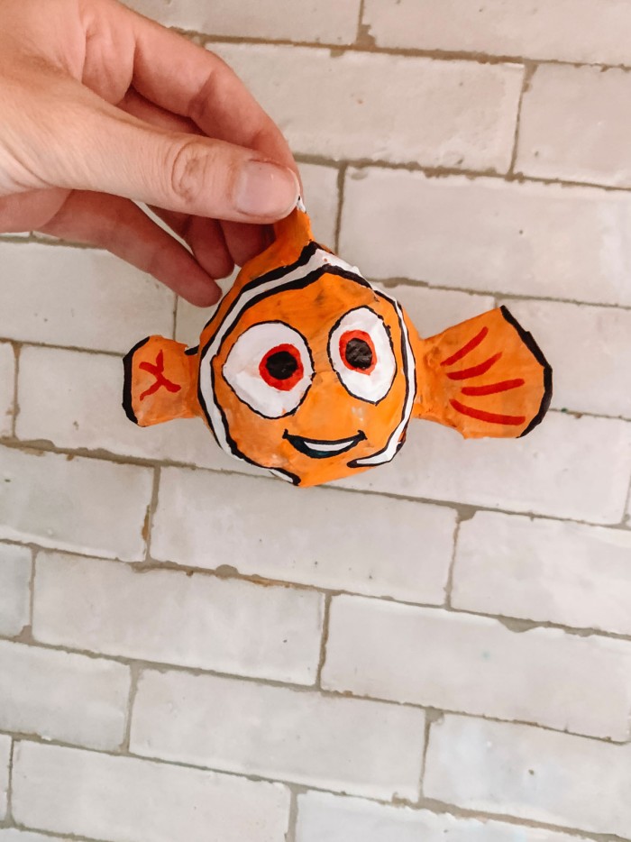 paper mache Finding Nemo held in front of a Tile wall