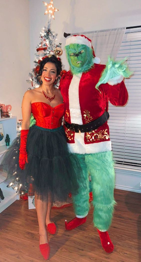 Two people dressed up as the Grinch and Martha May standing in front of a Christmas tree. 