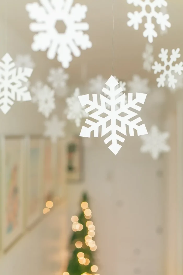 Snowflakes hanging from clear string on the ceiling. 