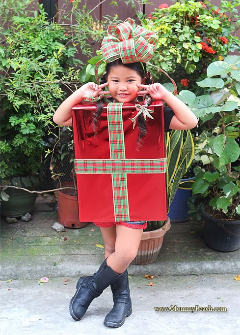 Girl dressed as a Christmas present with a bow on her head. 
