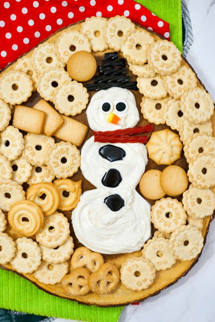 Frosting in the shape of a snowman surrounded by cookies. 