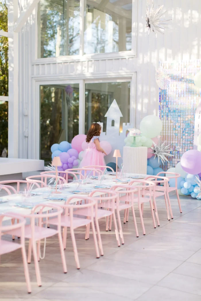 pastel frozen themed birthday party with long kids table and balloons behind it