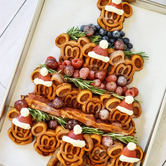 Mickey waffles layered with bacon and fruits in the shape of a tree. 