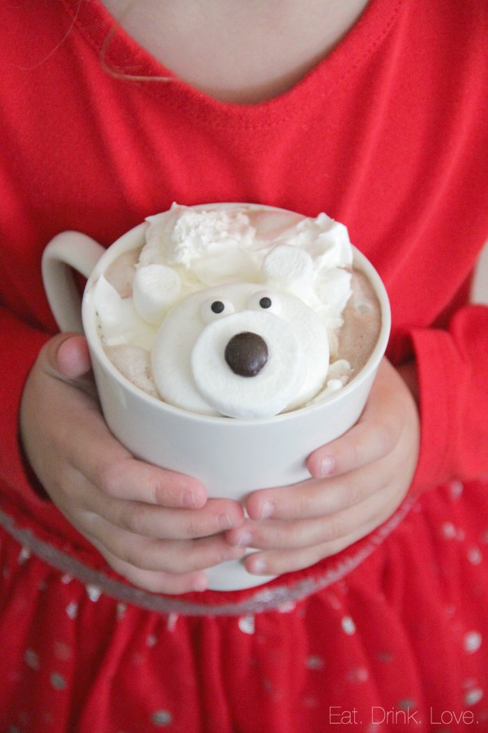 Child holding a mug of hot chocolate with marshmallows in the shape of a polar bear.