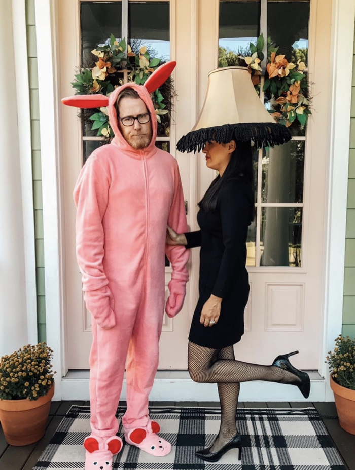 Man dressed as a bunny and woman dressed as a lamp, both standing in front of a door. 