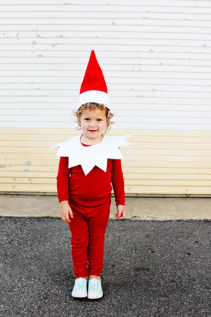 Child wearing a red outfit that looks like Elf on the Shelf. 