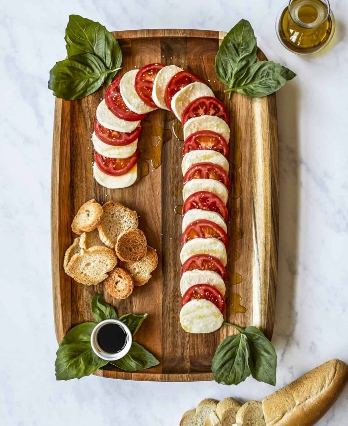 Tomatoes and cheese in the shape of a candy cane on a wooden board.