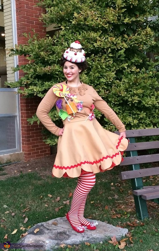Woman standing outside dressed as a gingerbread girl with striped stockings. 