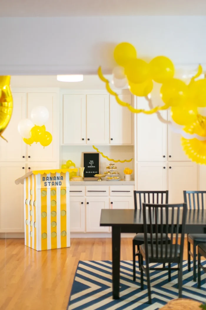 Banana themed party with yellow balloons and a banana stand. 