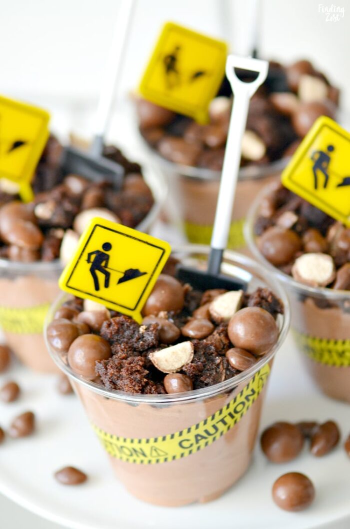 Chocolate dessert cups that have construction tape, signs and a little shovel as a spoon.