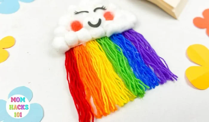 Cloud made out of cotton balls with strings coming out of the bottom in rainbow colors. 