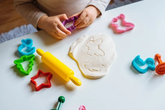 Playdough rolled out next to cookie cutouts. 