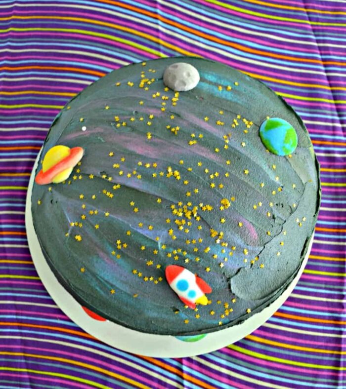 Black cake made to look like space with small planet figures. 