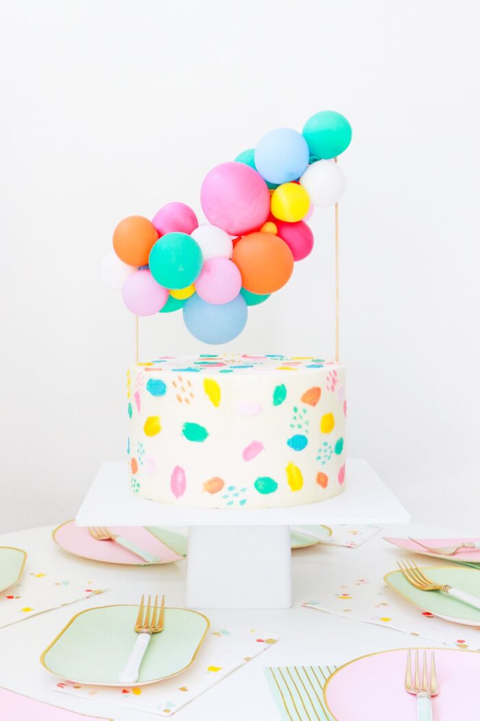 Birthday cake with a mini balloon topping on top. 