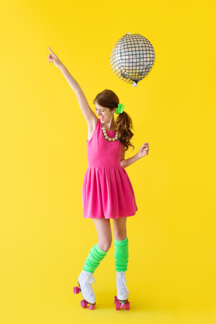 Woman standing with a disco balloon and roller skates on. 