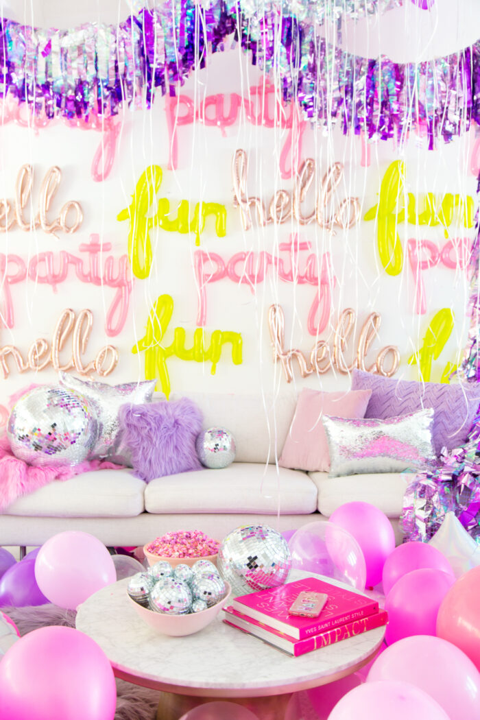 Scene of living room with balloons everywhere and text balloons on the wall. 