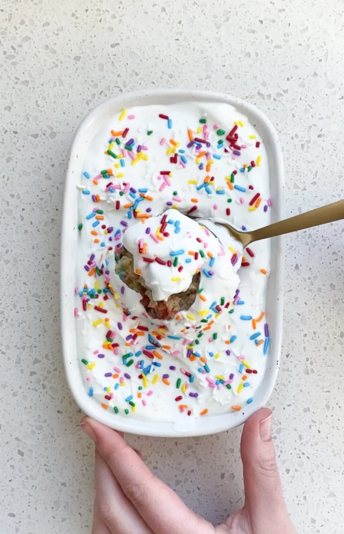 Small baking dish with baked oats and sprinkles on top with a spoon taking a bite. 