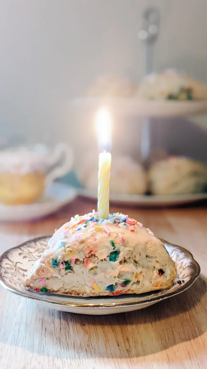 Scone with sprinkles and a birthday candle on top. 