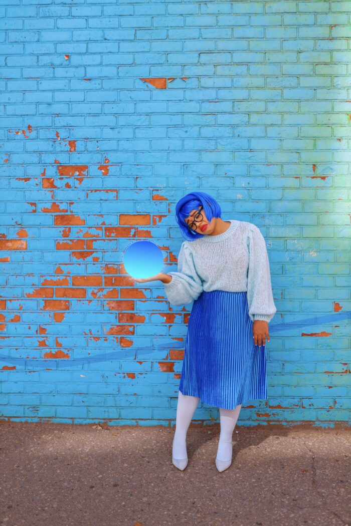 Woman dressed as "sadness" from Inside Out in front of a blue wall. 
