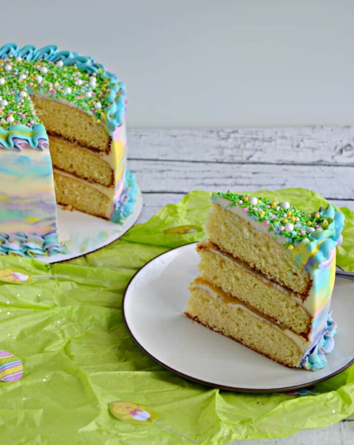 Watercolor triple layer cake with a slice on a plate. 