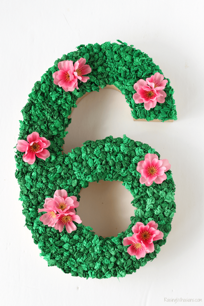 Number 6 decorated with green tissue paper and pink flowers. 