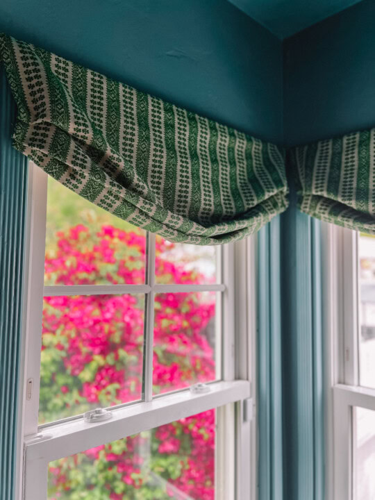 roman shade hanging above window in blue painted room