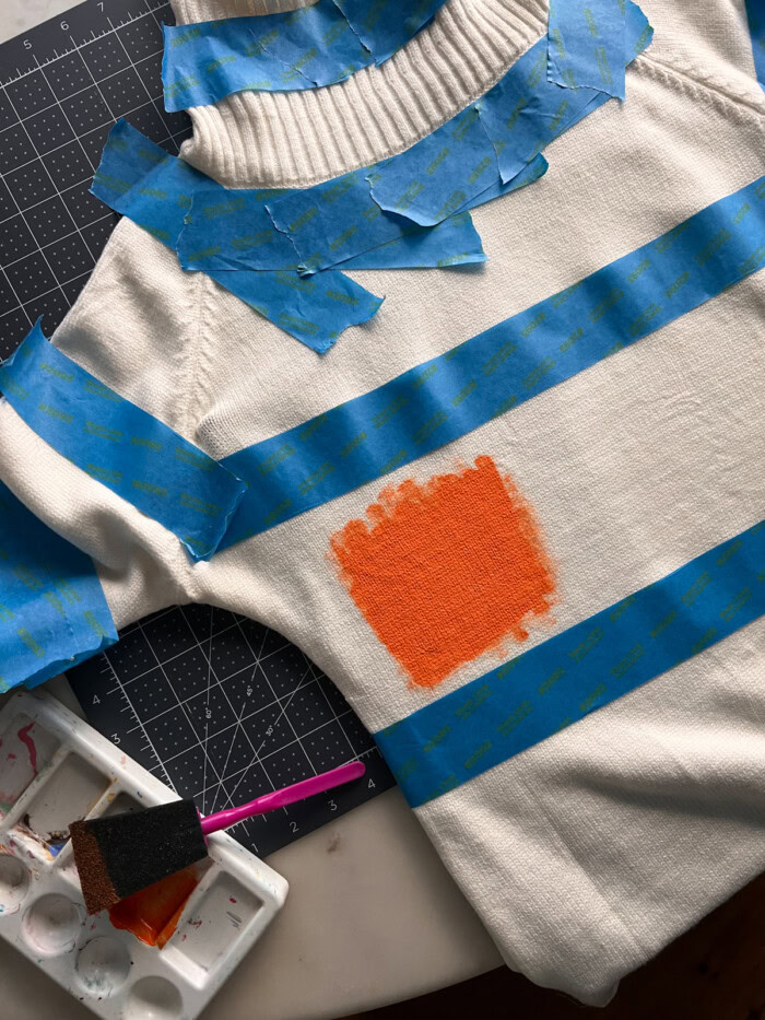 Painting orange stripes on sweater